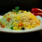 Plato de arroz amarillo con verduras frescas y coloridas