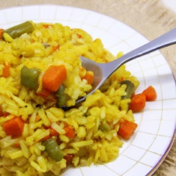 Plato de arroz amarillo con coloridas verduras cocinadas a la perfección, una deliciosa combinación llena de sabor y nutrientes.
