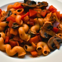 Plato de macarrones vegetarianos con salsa de tomate, setas y variedad de verduras frescas.