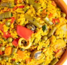 Imagen de una colorida paella vegana con variedad de verduras frescas y condimentos